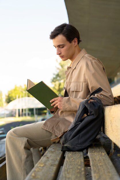屋外で本を読んでいる側面図の男