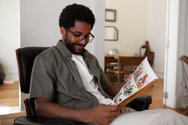 Вид сбоку мужчина читает комиксы дома