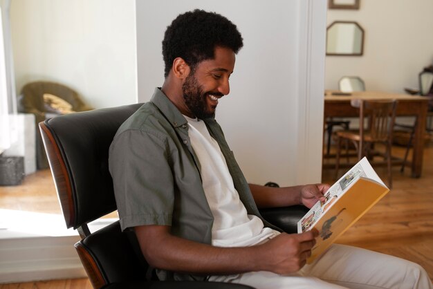 Side view man reading comics at home