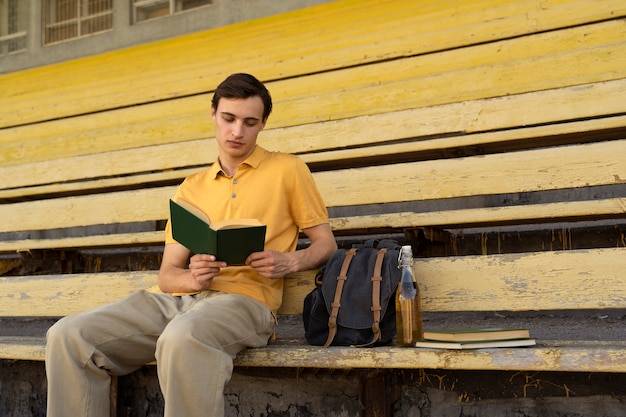 Free photo side view man reading in grandstands