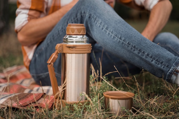 Side view of man relaxing outdoors with thermos