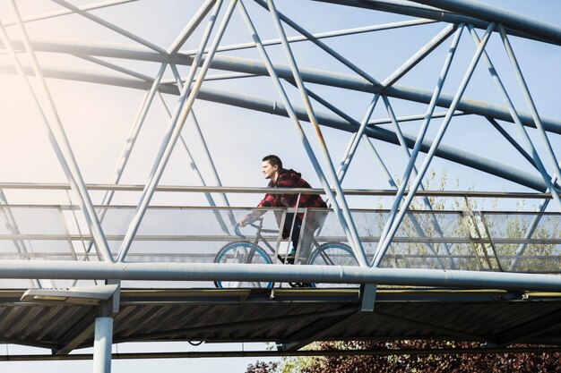 Вид сбоку человек, езда на велосипеде на мосту