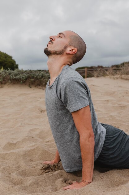 Side view of man on sand doing yoga
