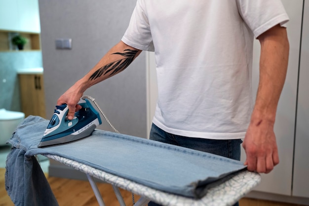 Free photo side view man servant ironing pants