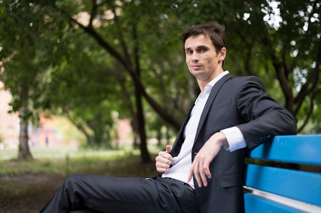 Side view of man sitting on blue bench