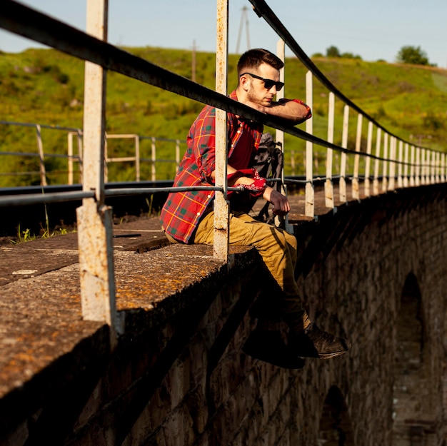 Free photo side view man sitting at bridge edge