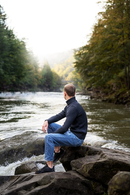 side view man sitting by the river