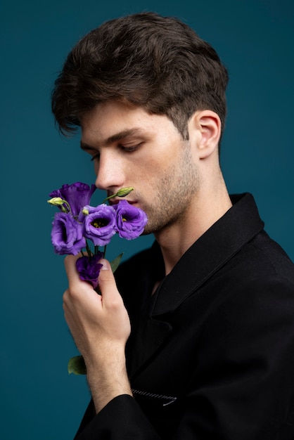 Free photo side view man smelling purple flower