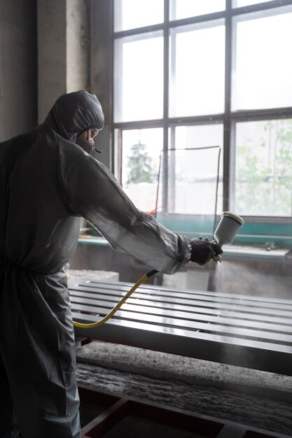 Side view man spraying powder paint from a gun