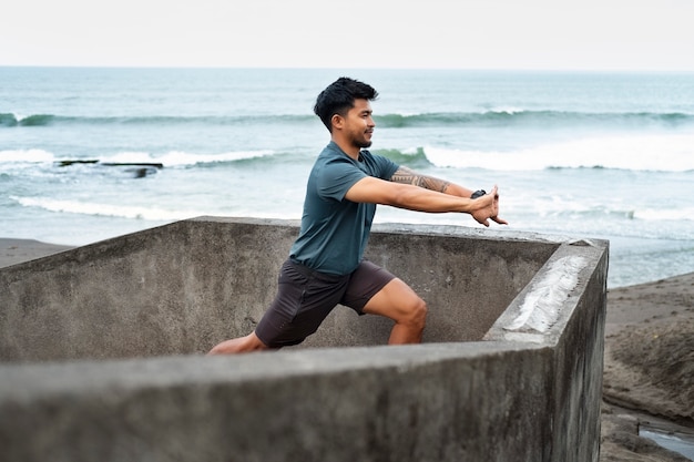 Free photo side view man stretching at beach