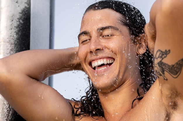 Бесплатное фото Вид сбоку мужчина принимает душ на открытом воздухе