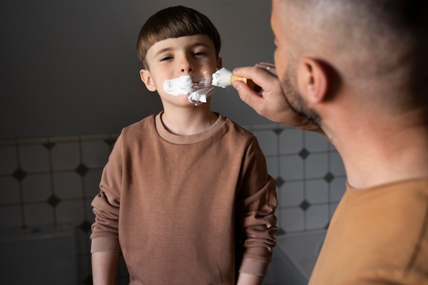 Side view man teaching kid how to shave