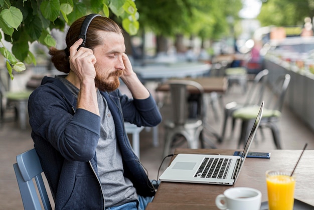 Side view of man at terrace with headphones and laptop