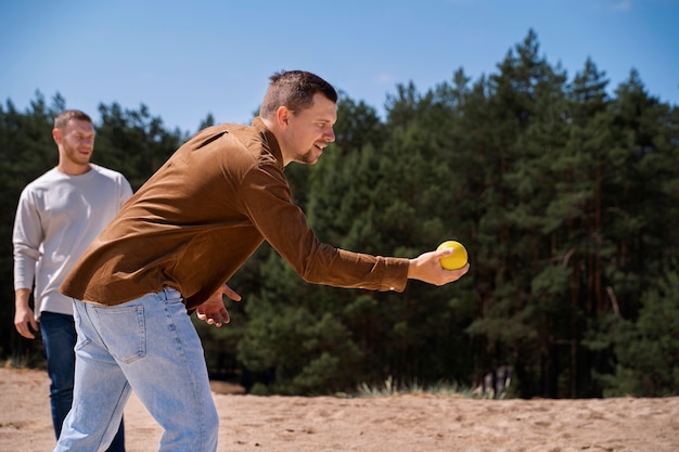 Вид сбоку мужчина бросает желтый мяч