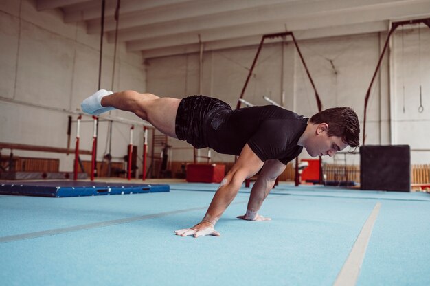 Side view man training with parallel bars