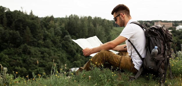 Foto gratuita uomo di vista laterale che viaggia da solo lettura mappa