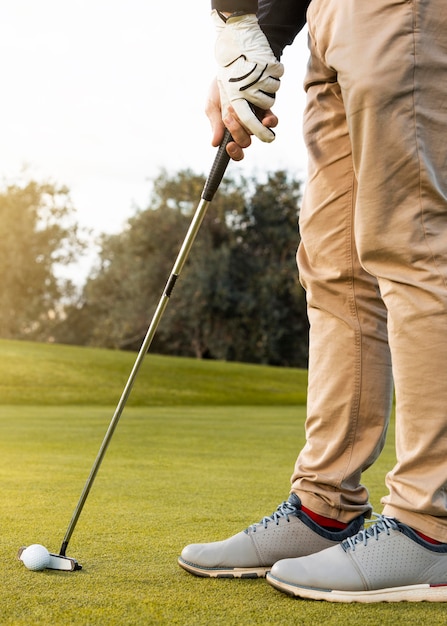 Side view of man using club to hit the golf ball