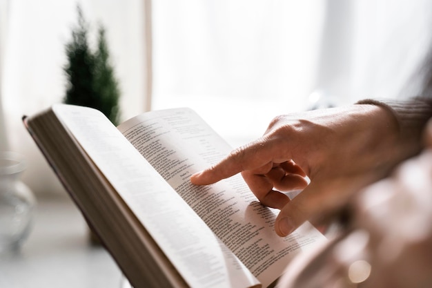 Вид сбоку человека, использующего палец для чтения Библии