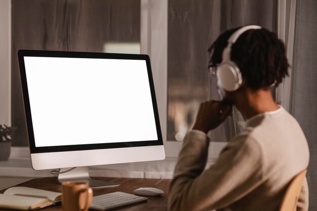 Side view of man using modern computer and headphones