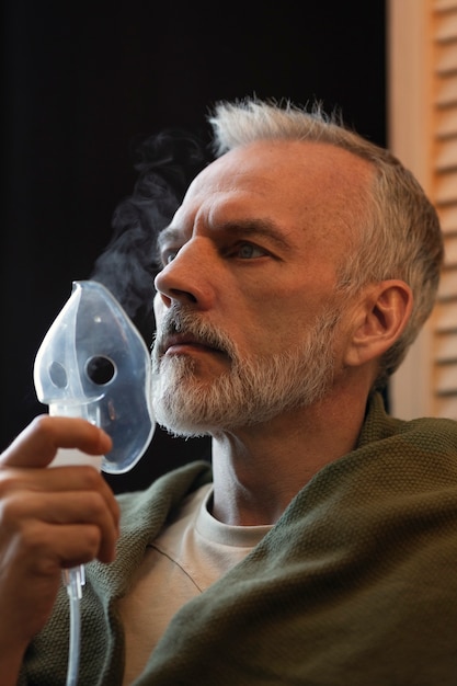 Side view man using nebulizer