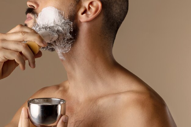 Free photo side view man using shaving cream