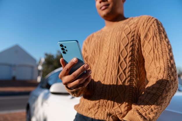 Бесплатное фото Вид сбоку человек, использующий смартфон на открытом воздухе