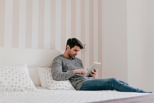 Uomo di vista laterale facendo uso della compressa sul letto