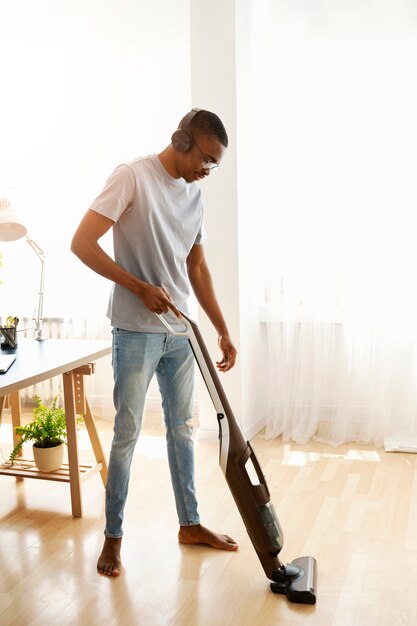 Side view man vacuuming floor