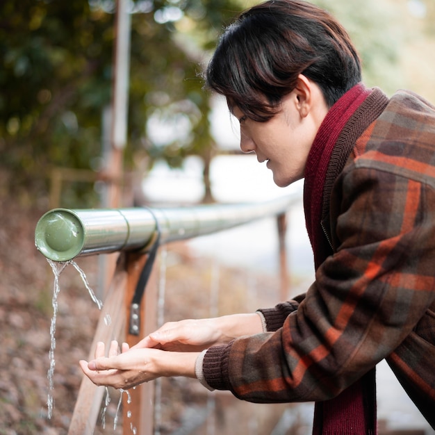 Free photo side view of man washing his hands outdoors