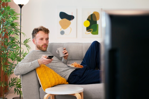 Free photo side view man watching news on tv