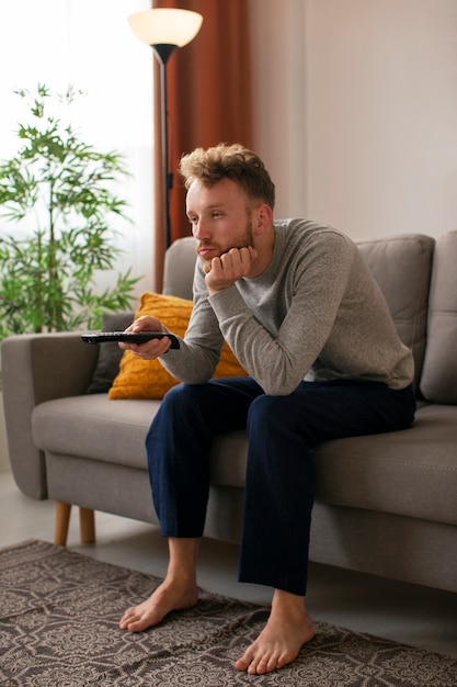 Free photo side view man watching news on tv