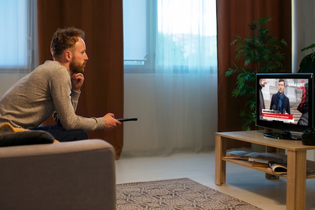 Uomo di vista laterale che guarda la tv