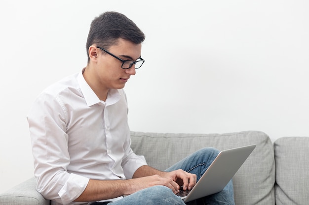 Free photo side view of man wearing glasses and looking at laptop