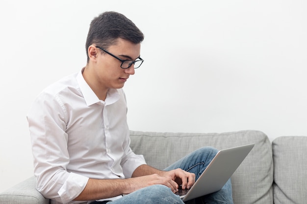 Side view of man wearing glasses and looking at laptop