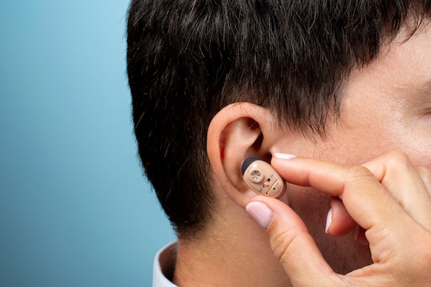 Free photo side view man wearing hearing aids