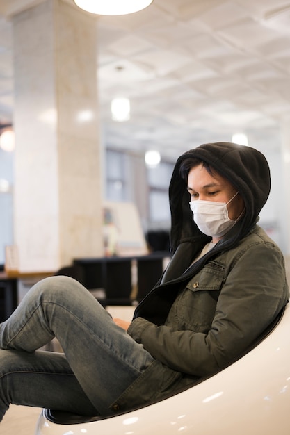 Free photo side view of man wearing medical mask lounging