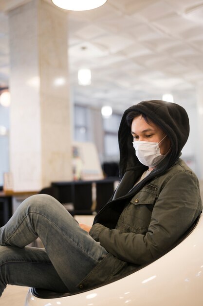 Vista laterale dell'uomo che indossa il bighellonare medico della maschera