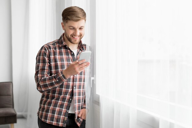 Side view man at window with mobile