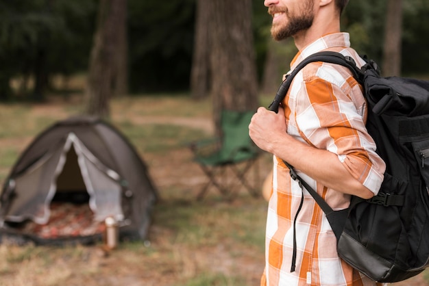 Side view of man with backpack camping with tent