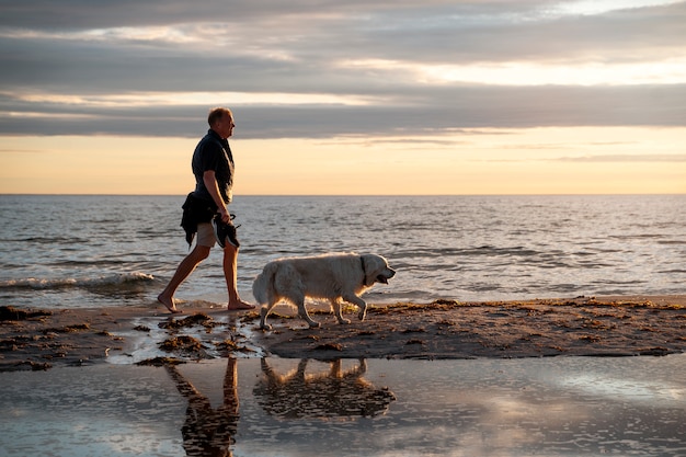 Вид сбоку мужчина с милой собакой на пляже