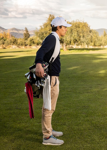 Side view of man with golf clubs on the field