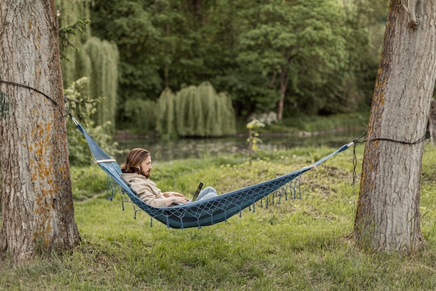 Side view of man with laptop in hammock