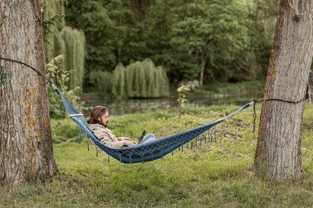 Side view of man with laptop in hammock