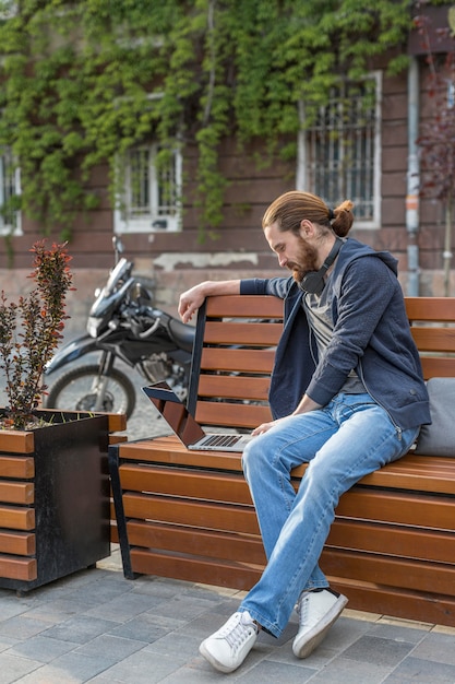 Foto gratuita vista laterale dell'uomo con il computer portatile all'aperto nella città