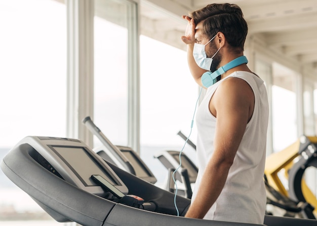 Side view of man with medical mask on the treadmill