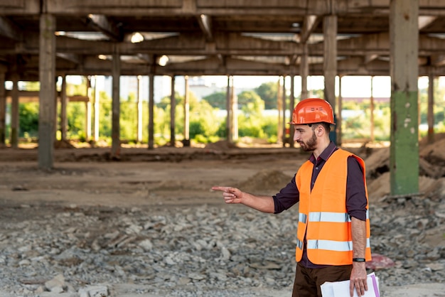 Free photo side view man with orange vest pointing