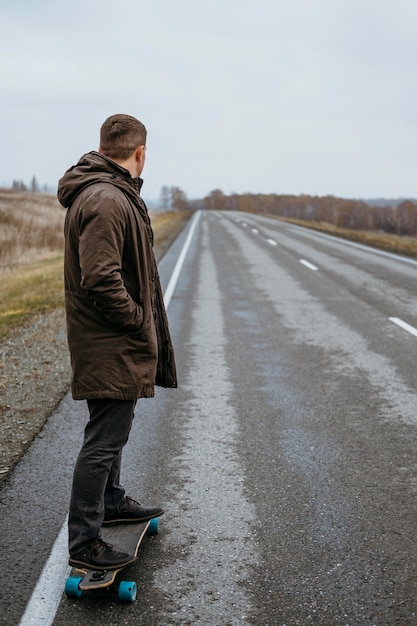 Free photo side view of man with skateboard on the road