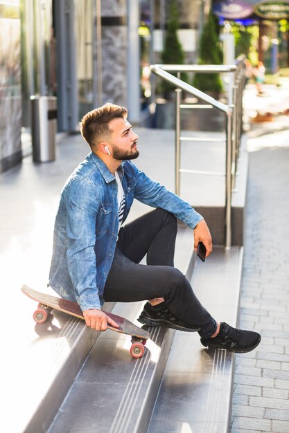 Side view of a man with skateboard sitting on staircase