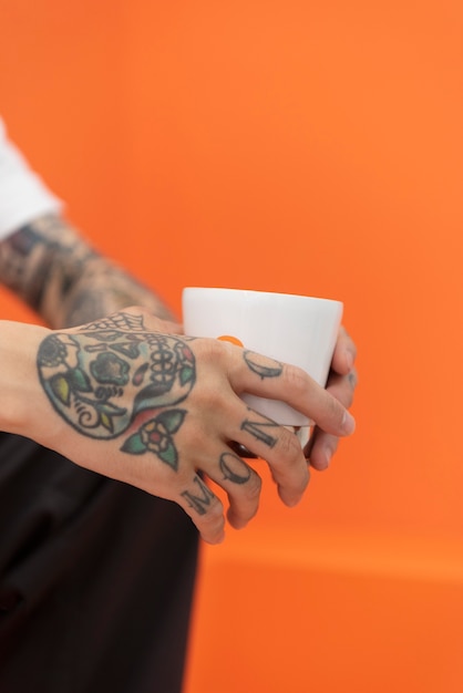 Vista laterale dell'uomo con i tatuaggi che tiene tazza di caffè al caffè