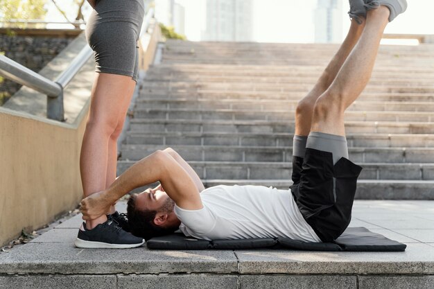 Side view of man and woman exercising together outdoors